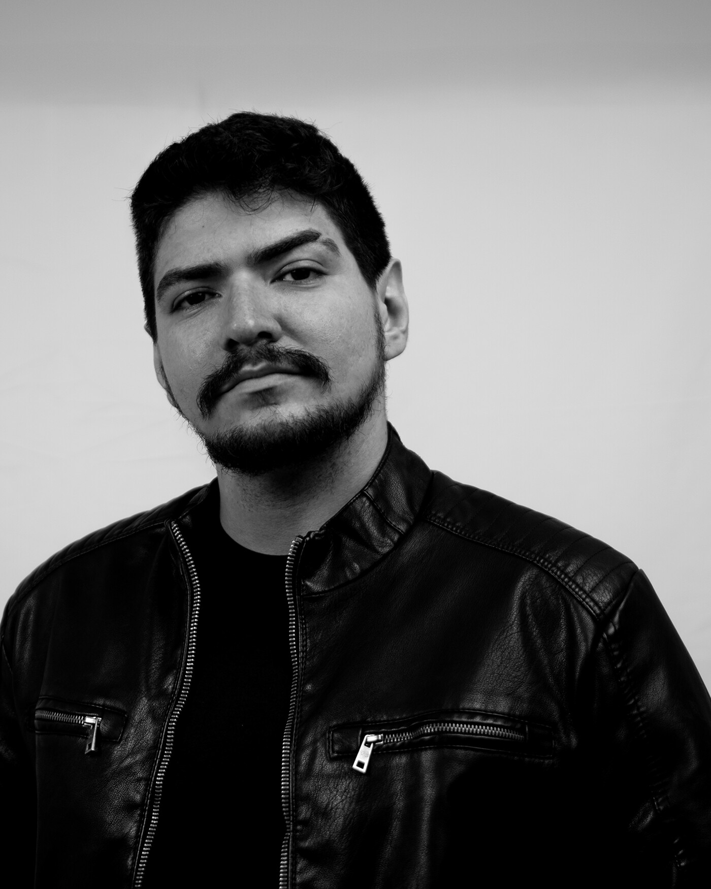 Retrato monocromático de Nilton Leoni Jr., de jaqueta de couro, olhando para a câmera